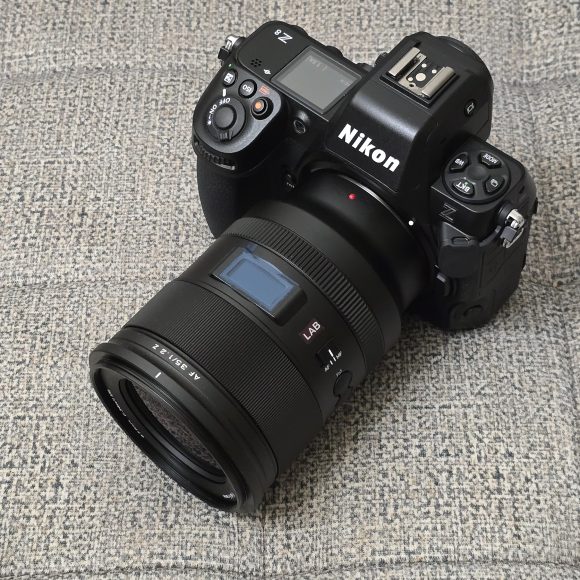 A Nikon Z series digital camera with a NIKKOR lens resting on a textured gray surface.