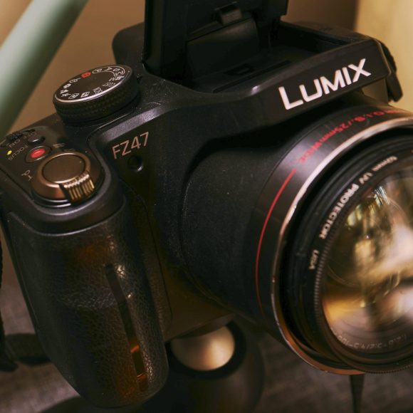 A close-up of a black Lumix FZ47 camera with a large lens and a red logo in the corner.
