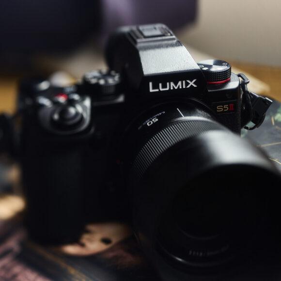 A Lumix S5 camera with a large lens sits on a surface, slightly blurred background.