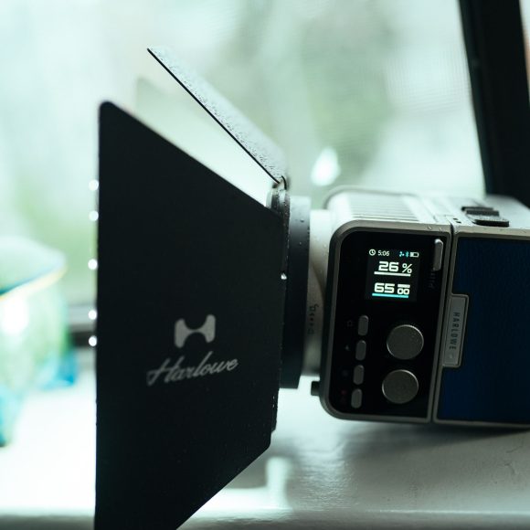 A vintage-style camera with a matte box sits on a windowsill next to a decorative jar.