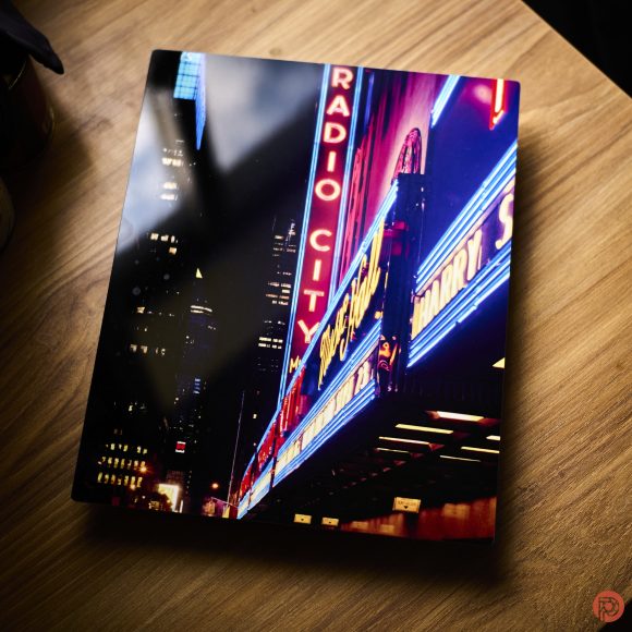 A glossy book with a Radio City sign cover rests on a wooden surface.