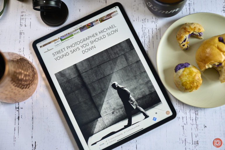 Tablet displaying an article about street photography beside a plate with pastries.