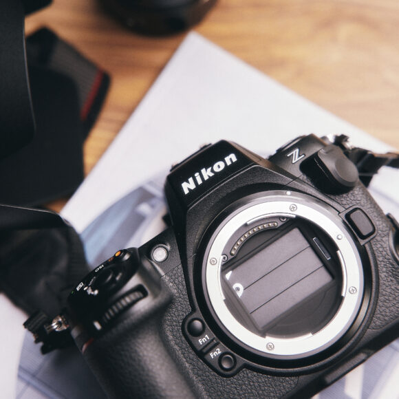 Nikon Z8 Firmware 3.0 - So Many Great Updates A Nikon Z camera body without a lens sits on a desk, next to a lens hood and some papers.