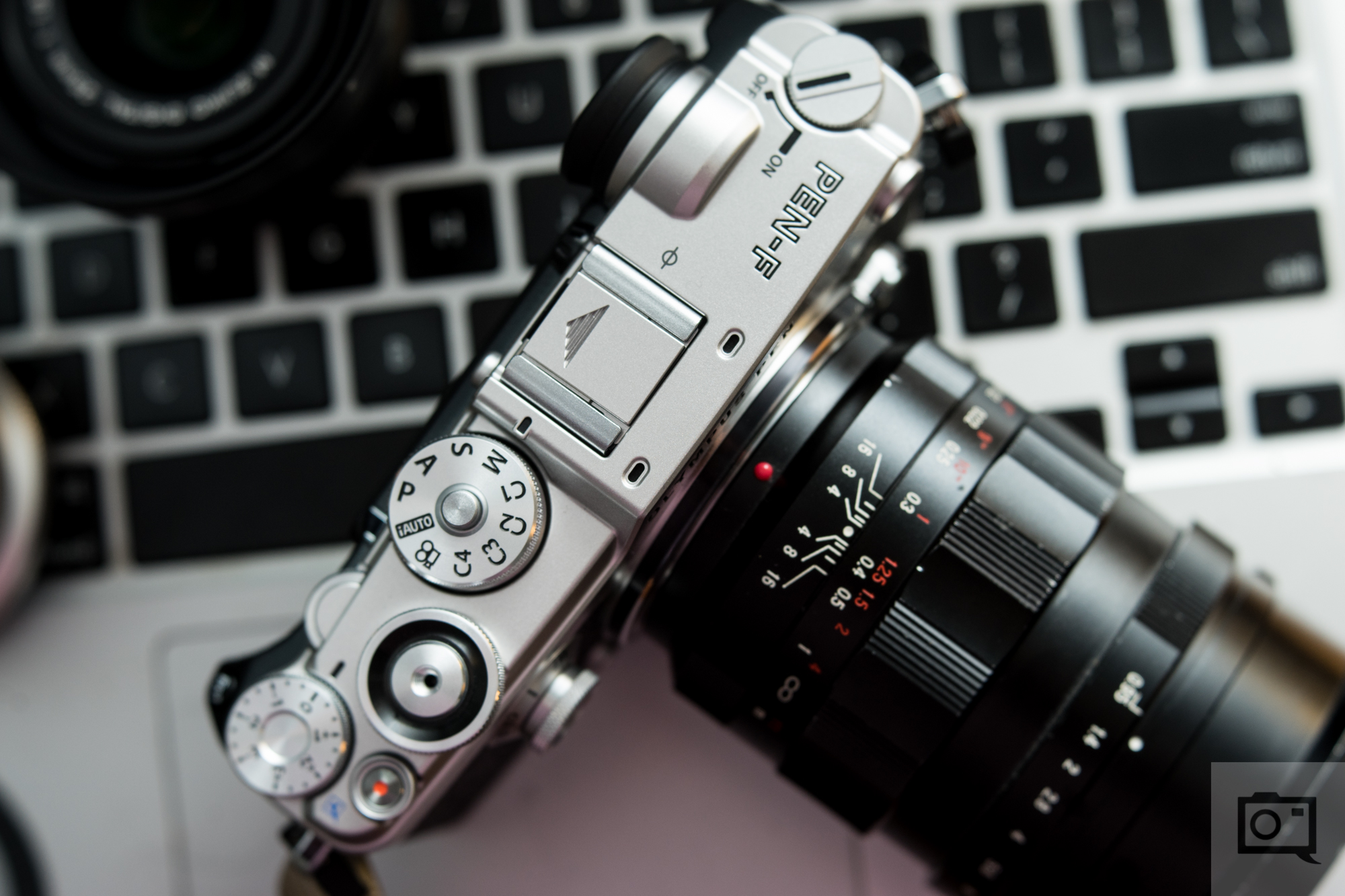 A vintage camera resting on a laptop keyboard, viewed from above.