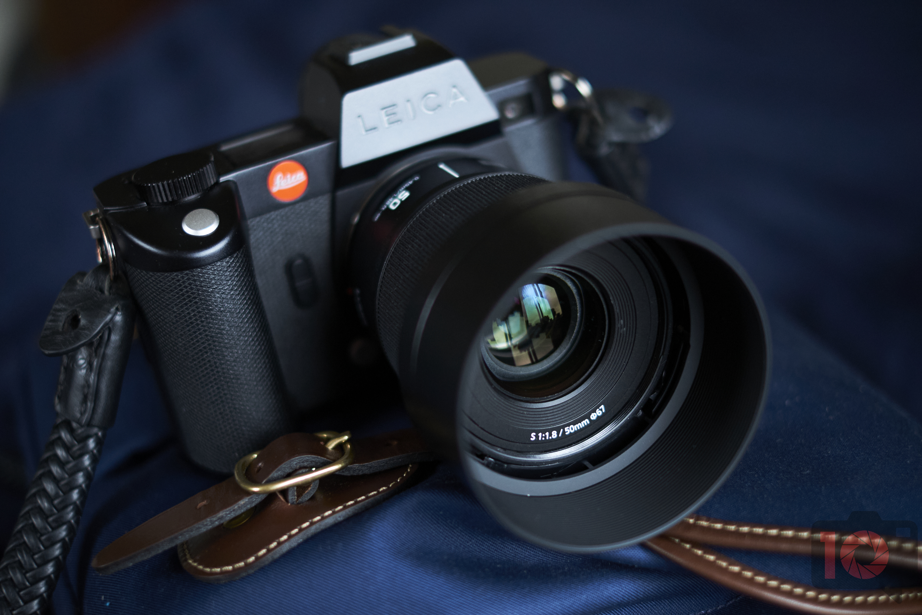 A close-up of a Leica camera with a large lens resting on a dark blue surface.