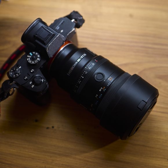 A black Sony camera with a large lens rests on a wooden surface.