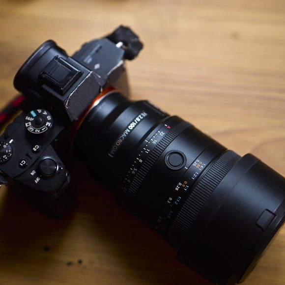 A black digital camera with a large lens sits on a wooden surface.