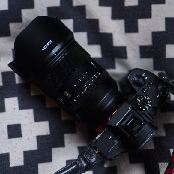 A Viltrox camera with a large lens rests on a black and white patterned pillow.