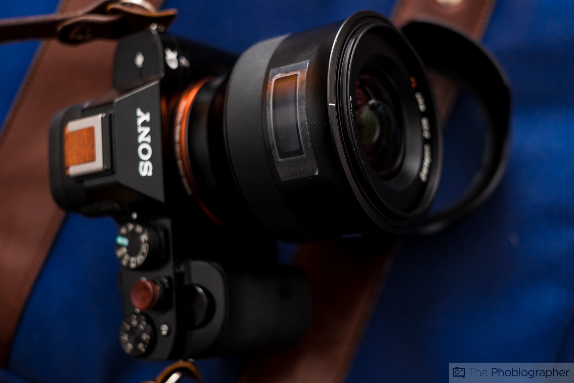 A close-up of a Sony camera with a large lens resting on a blue and brown bag.