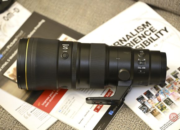 Nikon Z 600mm f6.3 Review: A Top-Notch, Affordable Super Telephoto A Nikon telephoto camera lens rests on magazines and papers on a desk.