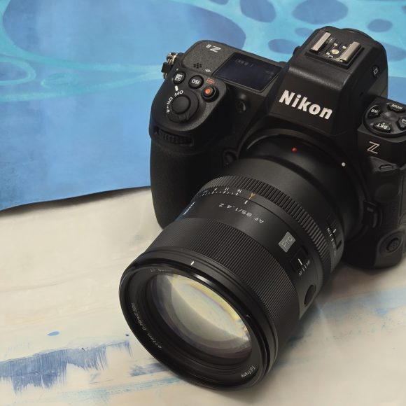 A Nikon Z camera with a large lens rests on a blue and white surface with abstract patterns.