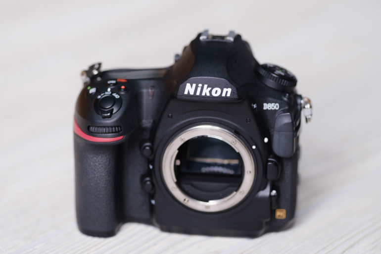 A Nikon D850 DSLR camera body without a lens, placed on a light-colored surface.