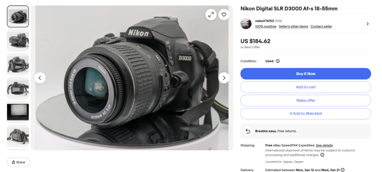 Nikon D3000 DSLR camera with 18-55mm lens displayed on a white surface, shown in a product listing.